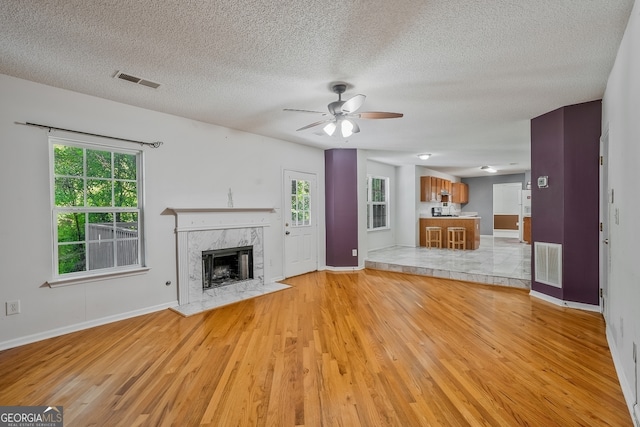 3524 Forest Downs Cv, Decatur, GA 30034 - unfurnished living room with light wood-type flooring, ceiling fan, baseboards, a textured ceiling, and a premium fireplace