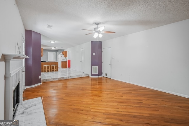 3524 Forest Downs Cv, Decatur, GA 30034 - unfurnished living room with light wood-style flooring, ceiling fan, baseboards, a textured ceiling, and a fireplace with flush hearth