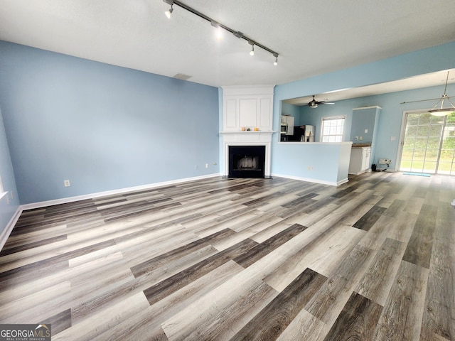 10900 Wittenridge Dr Unit H8, Alpharetta, GA 30022 - unfurnished living room with rail lighting, wood finished floors, ceiling fan, a large fireplace, and baseboards