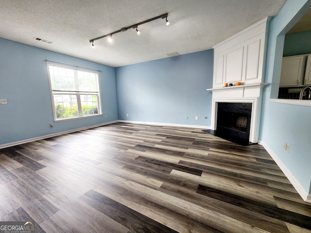 10900 Wittenridge Dr Unit H8, Alpharetta, GA 30022 - unfurnished living room featuring a fireplace, dark wood-style floors, track lighting, baseboards, and a textured ceiling