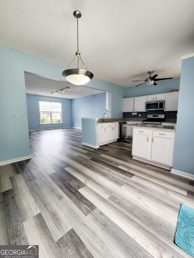 10900 Wittenridge Dr Unit H8, Alpharetta, GA 30022 - kitchen featuring stainless steel microwave, open floor plan, a peninsula, white cabinets, and range with gas cooktop
