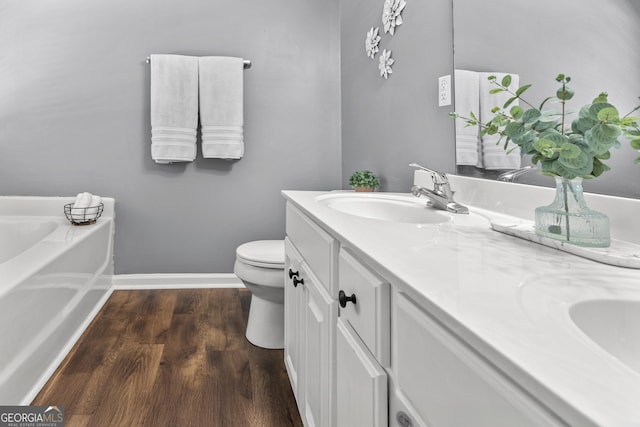 230 Hannah Dr, Colbert, GA 30628 - full bath with double vanity, wood finished floors, a garden tub, toilet, and baseboards