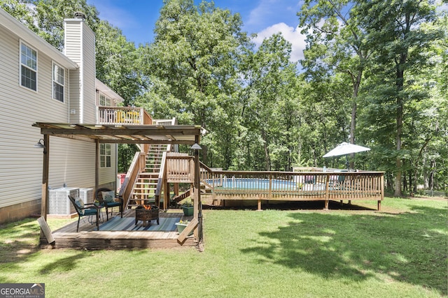 230 Hannah Dr, Colbert, GA 30628 - view of grassy yard with a deck, a fire pit, stairway, central AC unit, and view of wooded area