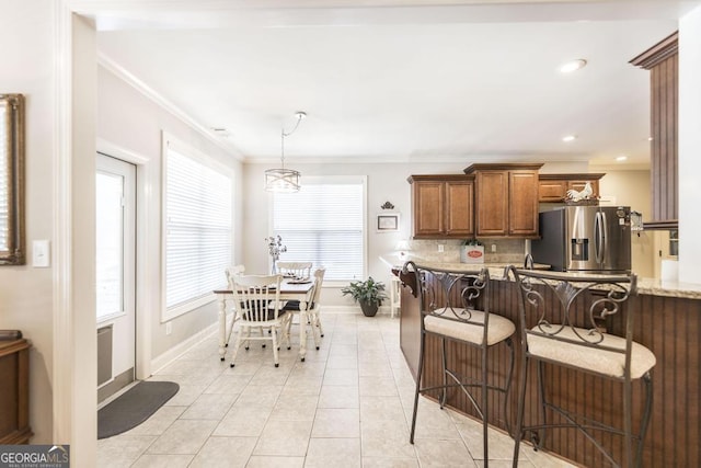215 Wilsons Creek Bnd, Bonaire, GA 31005 - kitchen featuring stainless steel refrigerator with ice dispenser, brown cabinetry, crown molding, backsplash, and baseboards
