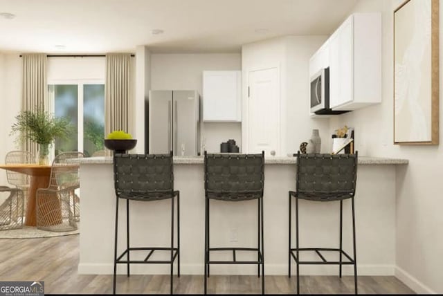134 Red Oak Dr, Barnesville, GA 30204 - kitchen with freestanding refrigerator, a peninsula, white microwave, white cabinets, and light wood-style floors