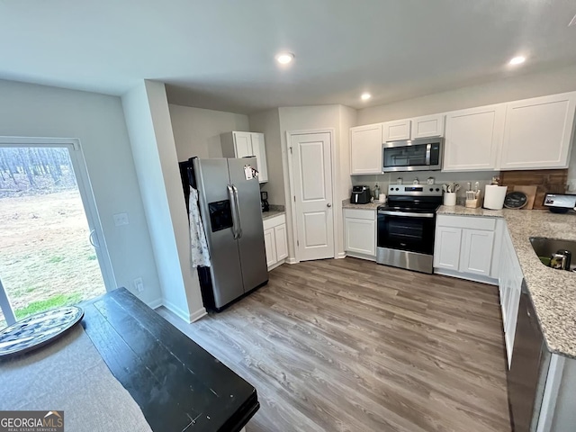 134 Red Oak Dr, Barnesville, GA 30204 - kitchen featuring appliances with stainless steel finishes, wood finished floors, white cabinets, recessed lighting, and light stone countertops