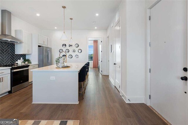 989 Bibbs Cir NW Unit 25, Atlanta, GA 30318 - kitchen with stainless steel appliances, wall chimney range hood, light countertops, tasteful backsplash, and dark wood-style flooring
