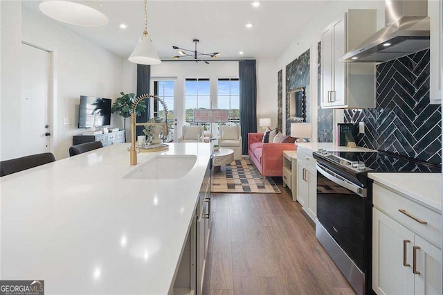 989 Bibbs Cir NW Unit 25, Atlanta, GA 30318 - kitchen with wall chimney exhaust hood, electric stove, a sink, open floor plan, and light countertops