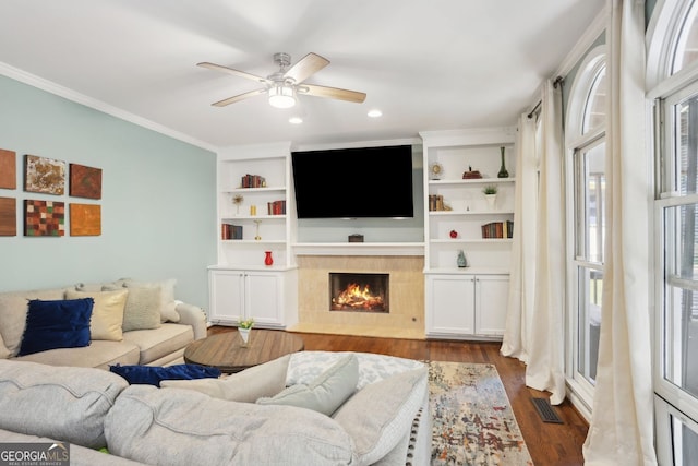2567 Briers N Dr, Dunwoody, GA 30360 - living area with a tiled fireplace, dark wood-style flooring, ceiling fan, crown molding, and built in features