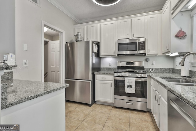 508 Las Brasis Ct, Peachtree City, GA 30269 - kitchen with stainless steel appliances, a sink, white cabinetry, ornamental molding, and dark stone counters