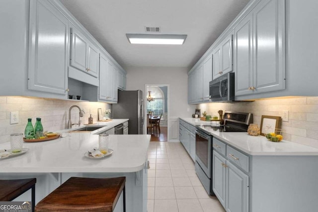 3027 Biltmore Woods Dr, Buford, GA 30519 - kitchen featuring stainless steel appliances, a peninsula, light countertops, decorative backsplash, and a sink