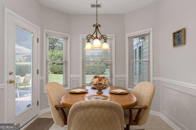 3027 Biltmore Woods Dr, Buford, GA 30519 - dining room featuring light tile patterned floors, a decorative wall, a chandelier, and wainscoting