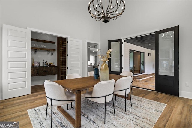 1604 Greendale Rd, Covington, GA 30014 - dining space featuring wood finished floors, a chandelier, a towering ceiling, and baseboards