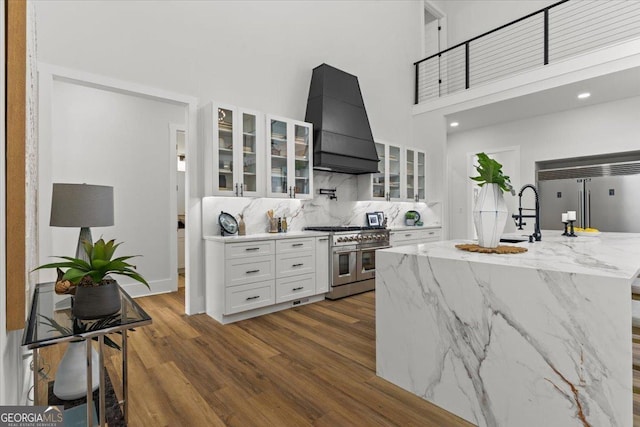1604 Greendale Rd, Covington, GA 30014 - kitchen with high quality appliances, premium range hood, white cabinets, dark wood-type flooring, and tasteful backsplash