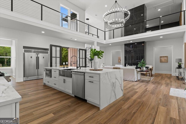 1604 Greendale Rd, Covington, GA 30014 - kitchen featuring appliances with stainless steel finishes, a high ceiling, a sink, white cabinets, and healthy amount of natural light