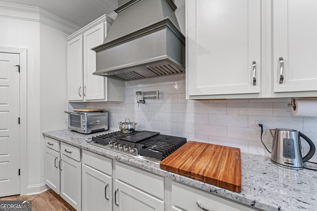 2036 Jefferson Hall Dr, Monroe, GA 30656 - kitchen featuring custom exhaust hood, white cabinetry, stainless steel gas stovetop, and backsplash