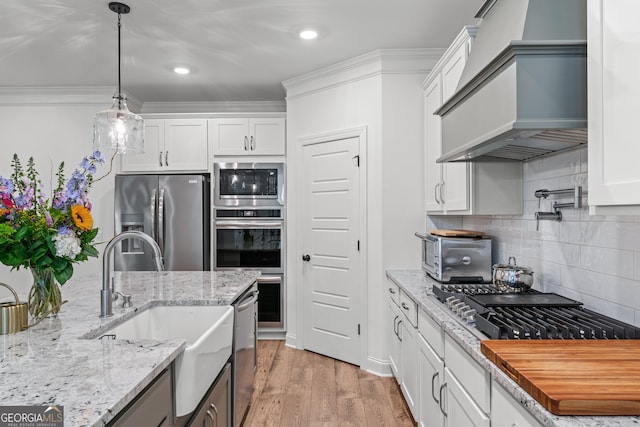 2036 Jefferson Hall Dr, Monroe, GA 30656 - kitchen with stainless steel appliances, premium range hood, white cabinetry, and ornamental molding