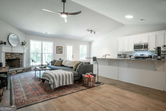 35 Westwood St, Danielsville, GA 30633 - living area featuring vaulted ceiling, wood finished floors, ceiling fan, a fireplace, and track lighting