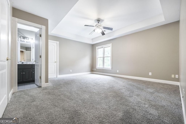 107 Julee Emilyn Dr, Bonaire, GA 31005 - unfurnished bedroom with a tray ceiling, light colored carpet, baseboards, connected bathroom, and a ceiling fan