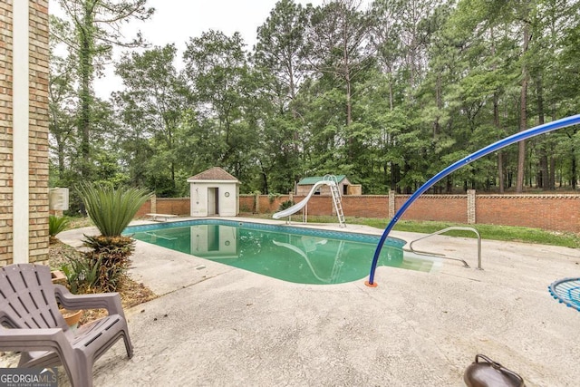 107 Julee Emilyn Dr, Bonaire, GA 31005 - view of swimming pool featuring a patio area, view of scattered trees, a water slide, a fenced backyard, and a diving board