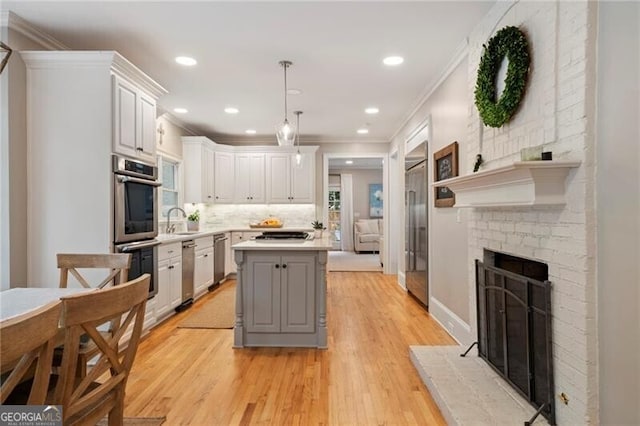 3894 Land O Lakes Dr NE, Atlanta, GA 30342 - kitchen with a fireplace, ornamental molding, appliances with stainless steel finishes, light countertops, and a kitchen island