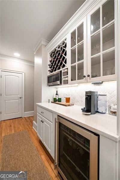 3894 Land O Lakes Dr NE, Atlanta, GA 30342 - indoor dry bar featuring wine cooler, ornamental molding, tasteful backsplash, light wood finished floors, and recessed lighting
