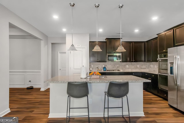 1243 Polk Xing, Mcdonough, GA 30252 - kitchen with appliances with stainless steel finishes, dark wood finished floors, backsplash, light stone counters, and recessed lighting