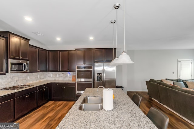1243 Polk Xing, Mcdonough, GA 30252 - kitchen with appliances with stainless steel finishes, open floor plan, dark brown cabinets, decorative backsplash, and decorative light fixtures