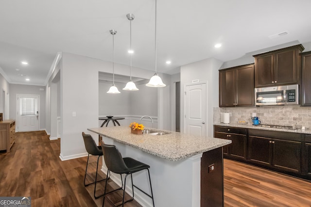1243 Polk Xing, Mcdonough, GA 30252 - kitchen with stainless steel appliances, light stone counters, dark brown cabinetry, a breakfast bar area, and decorative backsplash