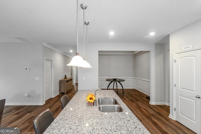 1243 Polk Xing, Mcdonough, GA 30252 - kitchen with dark wood-type flooring, light stone countertops, hanging light fixtures, a wainscoted wall, and recessed lighting