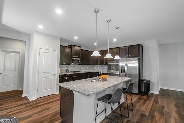 1243 Polk Xing, Mcdonough, GA 30252 - kitchen featuring appliances with stainless steel finishes, dark brown cabinets, tasteful backsplash, dark wood-style flooring, and an island with sink