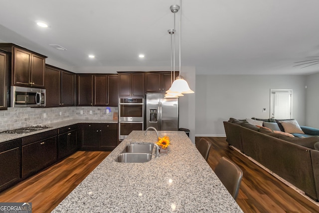 1243 Polk Xing, Mcdonough, GA 30252 - kitchen with appliances with stainless steel finishes, open floor plan, dark wood-type flooring, dark brown cabinets, and decorative backsplash