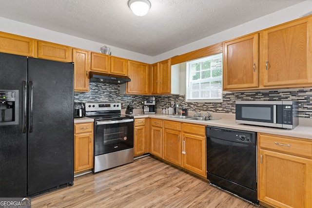 1450 Steam Engine Way NE, Conyers, GA 30013 - kitchen with black appliances, under cabinet range hood, light countertops, light wood-type flooring, and tasteful backsplash