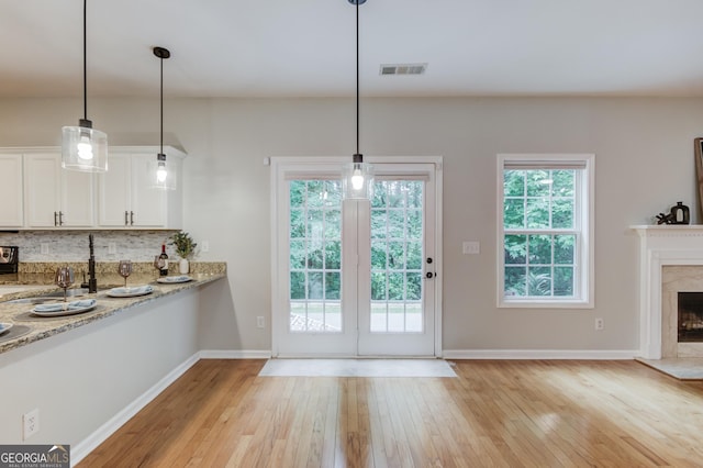 2725 Sedgeview Way, Buford, GA 30519 - kitchen featuring light wood-style floors, white cabinetry, decorative backsplash, light stone counters, and pendant lighting