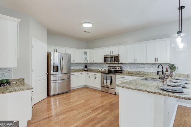 2725 Sedgeview Way, Buford, GA 30519 - kitchen featuring appliances with stainless steel finishes, a peninsula, white cabinetry, light wood finished floors, and backsplash