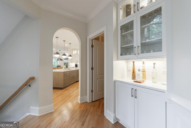 2101 Hunters Green Dr, Lawrenceville, GA 30043 - indoor dry bar featuring light wood-style flooring, arched walkways, crown molding, baseboards, and pendant lighting