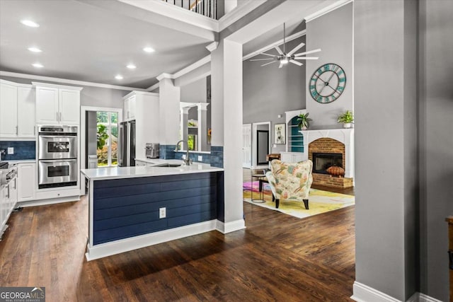 4251 Lantern Hill Dr, Dacula, GA 30019 - kitchen featuring a sink, appliances with stainless steel finishes, a ceiling fan, a high ceiling, and a brick fireplace