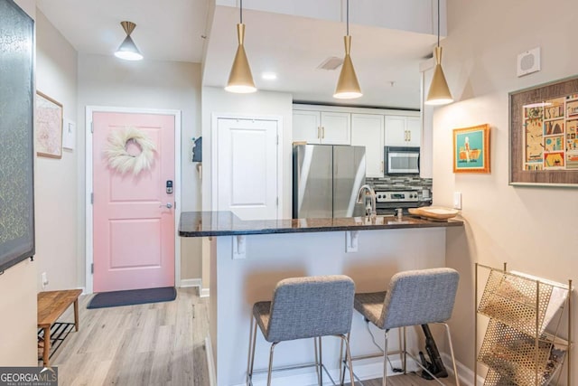 3040 Peachtree Rd NW Unit 1013, Atlanta, GA 30305 - kitchen featuring appliances with stainless steel finishes, light wood-type flooring, a breakfast bar, and white cabinets