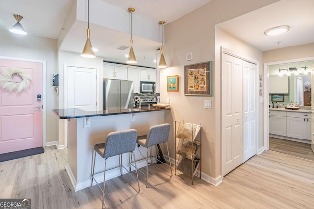 3040 Peachtree Rd NW Unit 1013, Atlanta, GA 30305 - kitchen with stainless steel appliances, a breakfast bar area, light wood-style flooring, and white cabinets
