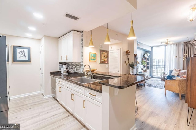 3040 Peachtree Rd NW Unit 1013, Atlanta, GA 30305 - kitchen featuring a sink, stainless steel dishwasher, light wood finished floors, white cabinets, and a peninsula