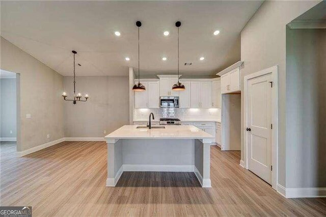 349 Creek Wood Park Dr, Ball Ground, GA 30107 - kitchen featuring appliances with stainless steel finishes, light wood-style flooring, backsplash, light countertops, and white cabinets