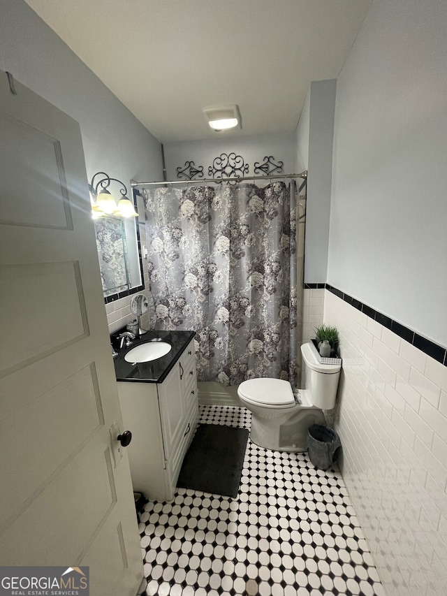 1103 E 2nd Ave SE, Rome, GA 30161 - bathroom featuring toilet, vanity, a shower with shower curtain, tile patterned floors, and tile walls