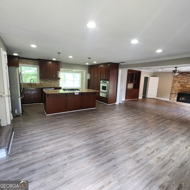 3140 Kipling Dr, Powder Springs, GA 30127 - kitchen featuring appliances with stainless steel finishes, open floor plan, a center island, wood finished floors, and crown molding