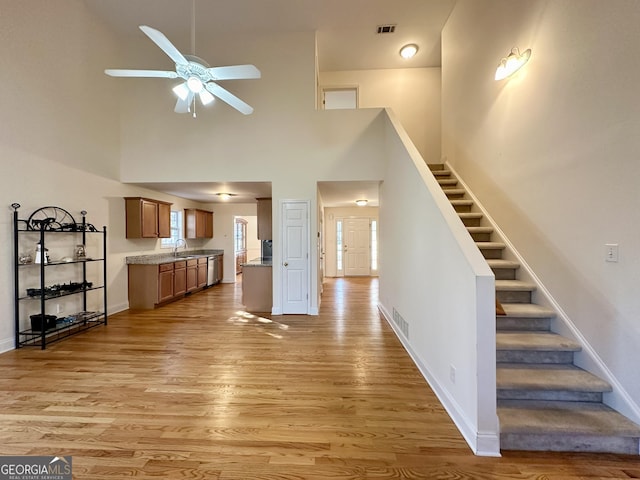 119 E Surry Ct, Athens, GA 30606 - unfurnished living room featuring stairs, a ceiling fan, light wood-style floors, and a high ceiling