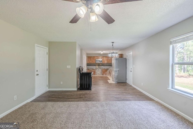7250 Old Chapel, Atlanta, GA 30349 - unfurnished living room featuring dark colored carpet, a ceiling fan, a textured ceiling, and a chandelier