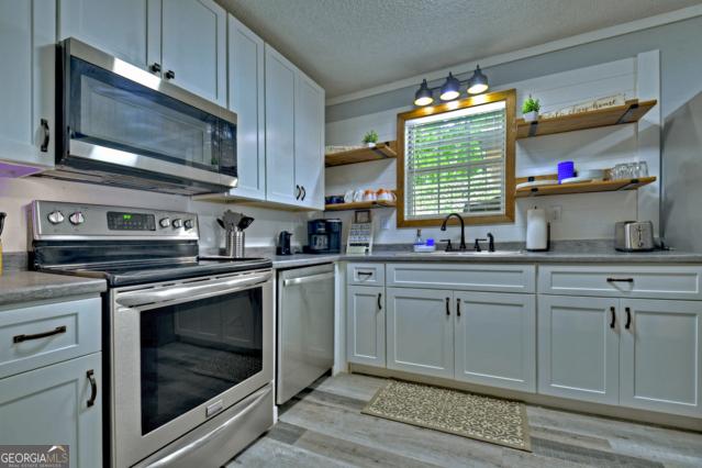 151 Padget Ln, Ellijay, GA 30540 - kitchen with stainless steel appliances, a sink, open shelves, white cabinets, and a textured ceiling