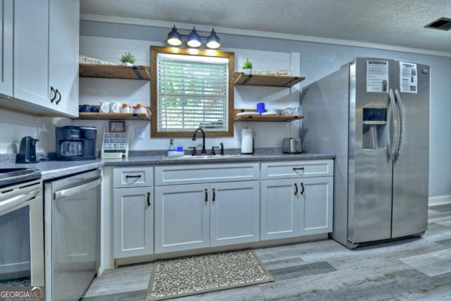 151 Padget Ln, Ellijay, GA 30540 - kitchen with appliances with stainless steel finishes, open shelves, light wood-type flooring, white cabinetry, and a sink