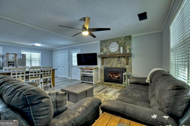 151 Padget Ln, Ellijay, GA 30540 - living room with ornamental molding, wood finished floors, a textured ceiling, ceiling fan, and a fireplace
