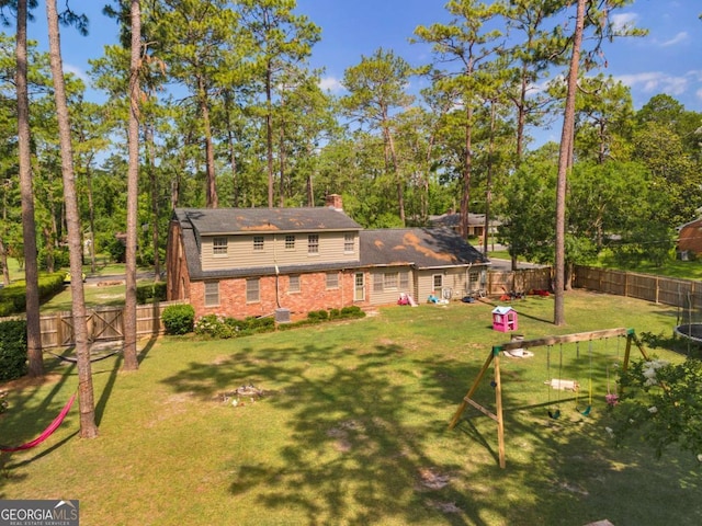 1504 Danora Dr, Waycross, GA 31501 - back of property featuring a fenced backyard, a chimney, view of wooded area, and brick siding