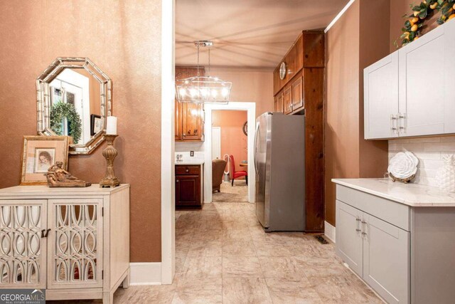 791 E Main St, Canton, GA 30114 - kitchen featuring freestanding refrigerator, tasteful backsplash, light countertops, pendant lighting, and a chandelier